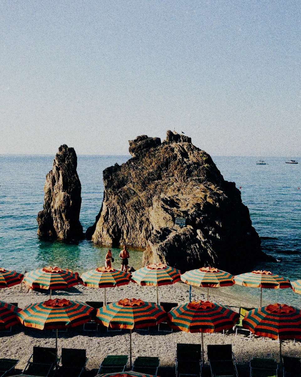 Gestreifte Sonnenschirme und Felsen vor Monterosso al Mare, mit Velvia 100 in Photonica bearbeitet