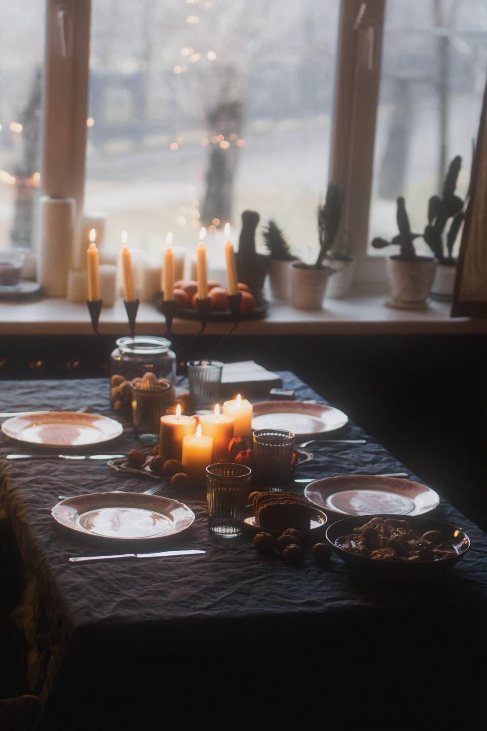 Una mesa de comedor a la luz de las velas junto a una ventana con difusión
