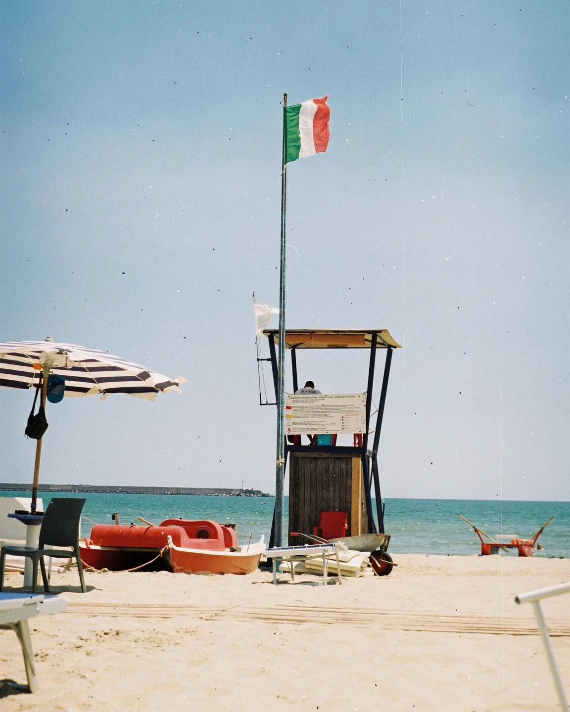 Beach and red lifeguard boat with added dust, fibres and scratches
