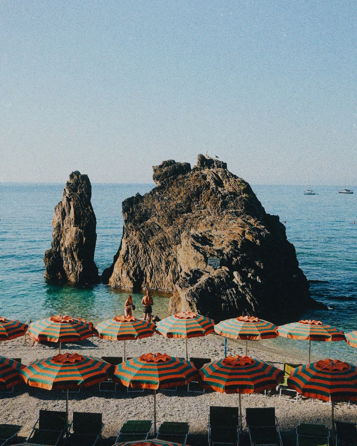 Sunlit coastal cliffs and beach umbrellas with a finished film-inspired treatment