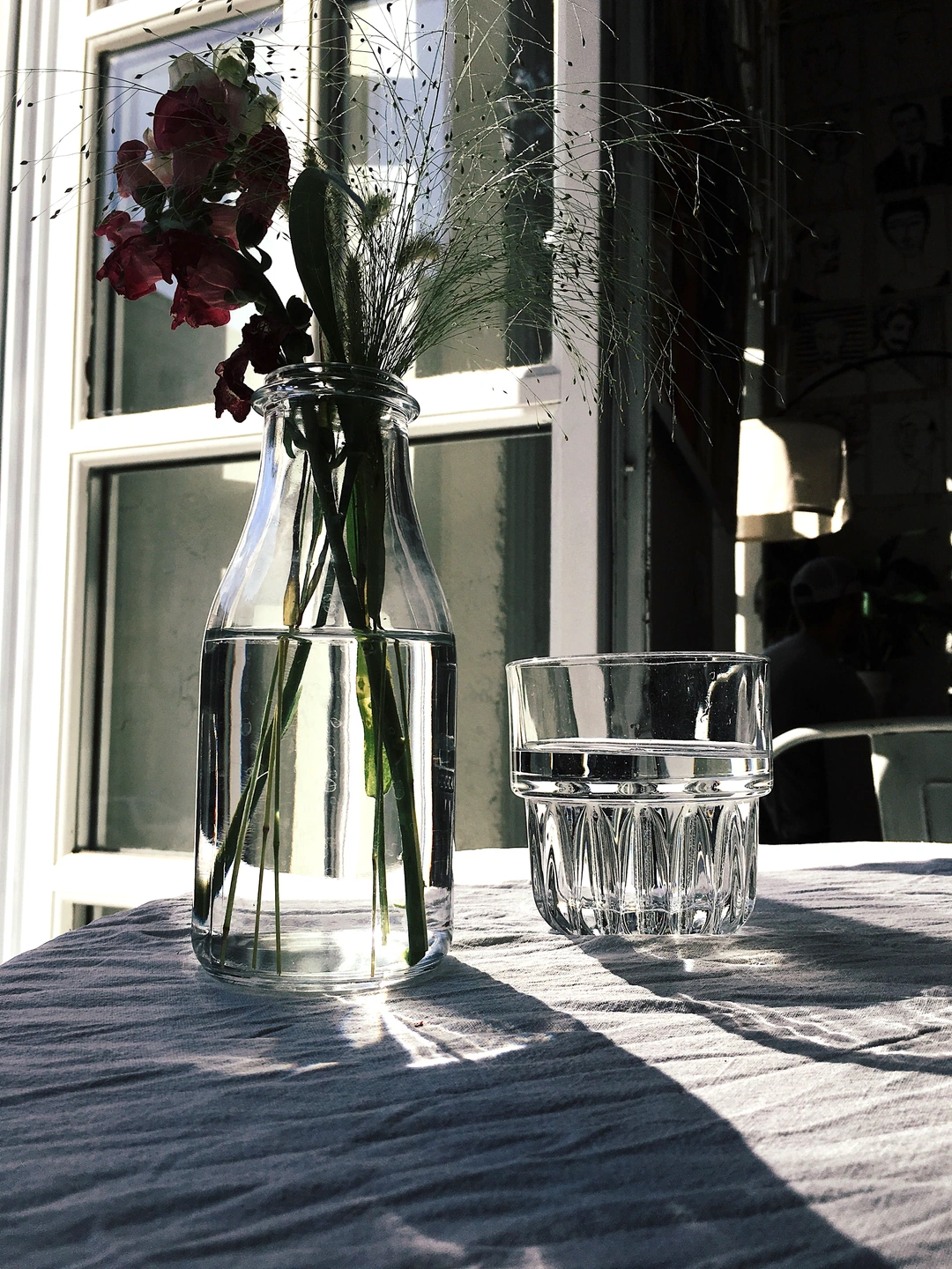 Glass and flowers beside a window with lifted exposure