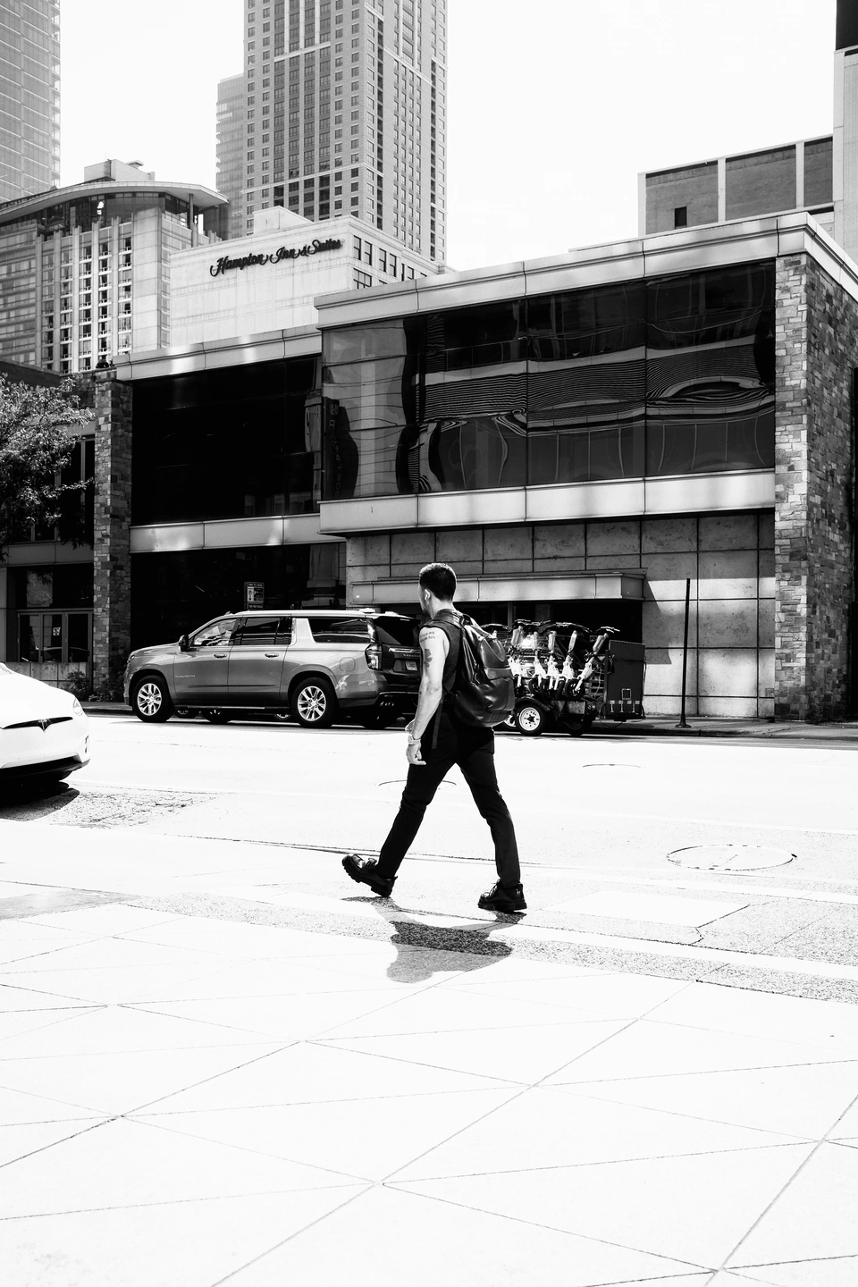 A pedestrian crossing a bright city pavement in black and white