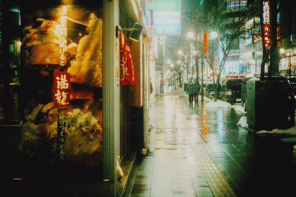 Illuminated signs reflected on a rainy Tokyo street, with the Night Glow preset in Photonica