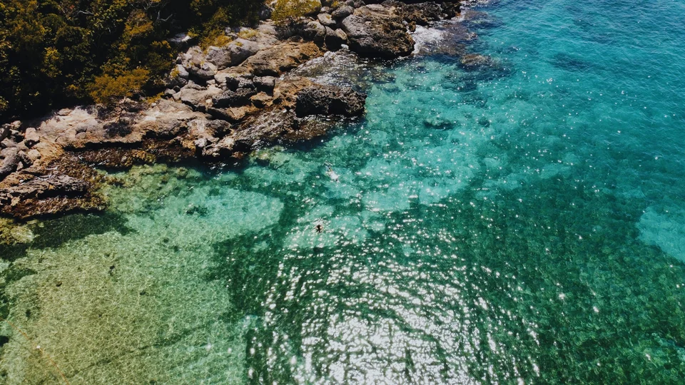 Clear turquoise water and sunlit rocks along a coastal cove, with the Sea Glass preset in Photonica